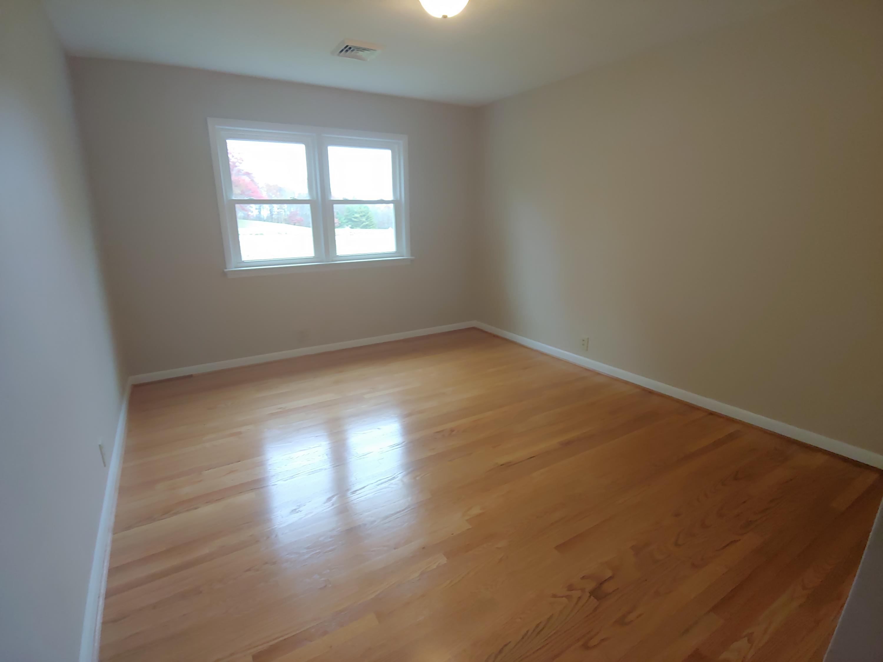 706 Alum Ridge Road Northwest Willis, VA 24380 - Photo 27 of 56 an empty room with wooden floor and windows