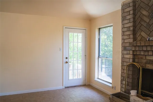 a view of an empty room with a fireplace and a window