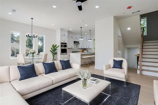 a living room with furniture kitchen view and a chandelier