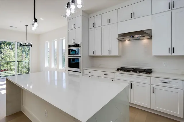 a large kitchen with cabinets a sink a window and stainless steel appliances