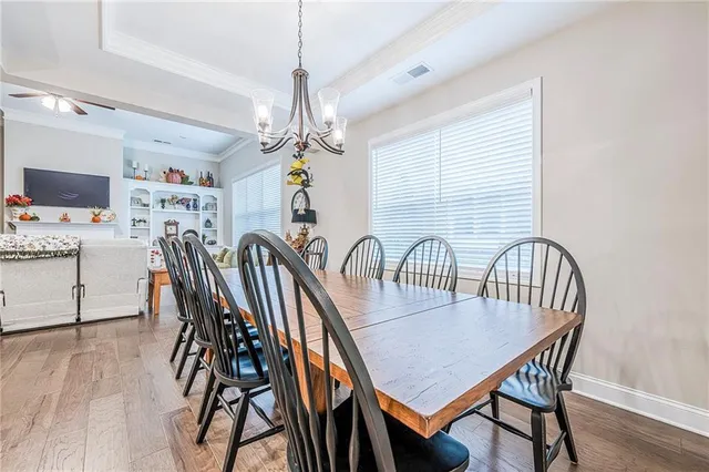 a dining room with wooden floor a chandelier a wooden table and chairs