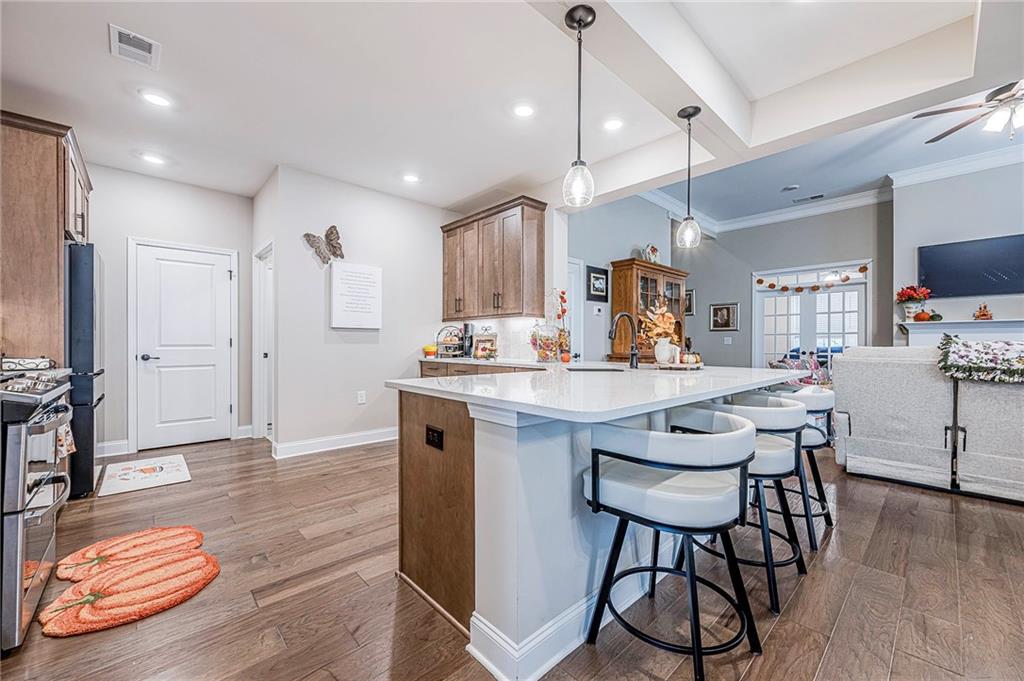 701 Calypso Way Cumming, GA 30040 - Photo 16 of 54 a kitchen with stainless steel appliances kitchen island granite countertop a stove a sink a refrigerator and chairs with wooden floor