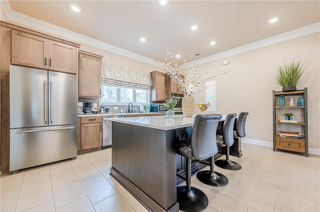701 Calypso Way Cumming, GA 30040 - Photo 49 of 54 a kitchen with kitchen island a refrigerator a stove a sink a dining table and chairs
