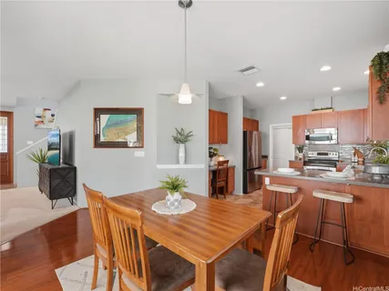 a kitchen with stainless steel appliances kitchen island granite countertop a dining table chairs and a refrigerator