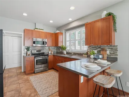 a kitchen with stainless steel appliances granite countertop a sink a stove a refrigerator cabinets and dining table