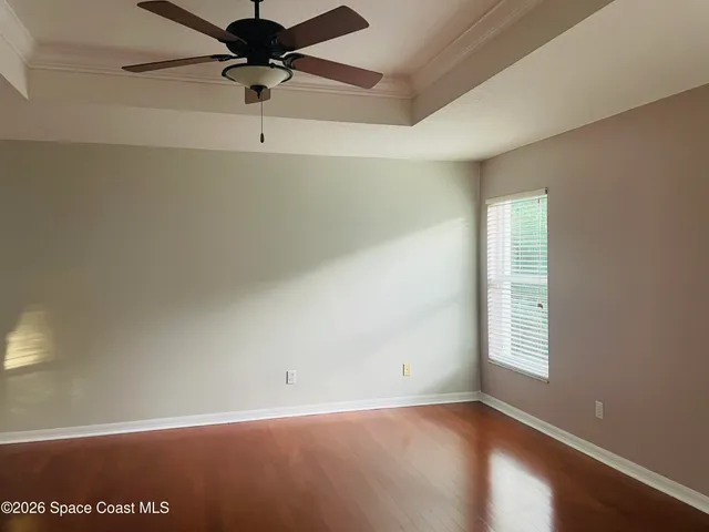an empty room with a ceiling fan and wooden floor