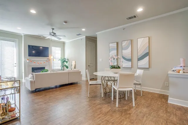 a living room with furniture a dining table wooden floor and a fireplace
