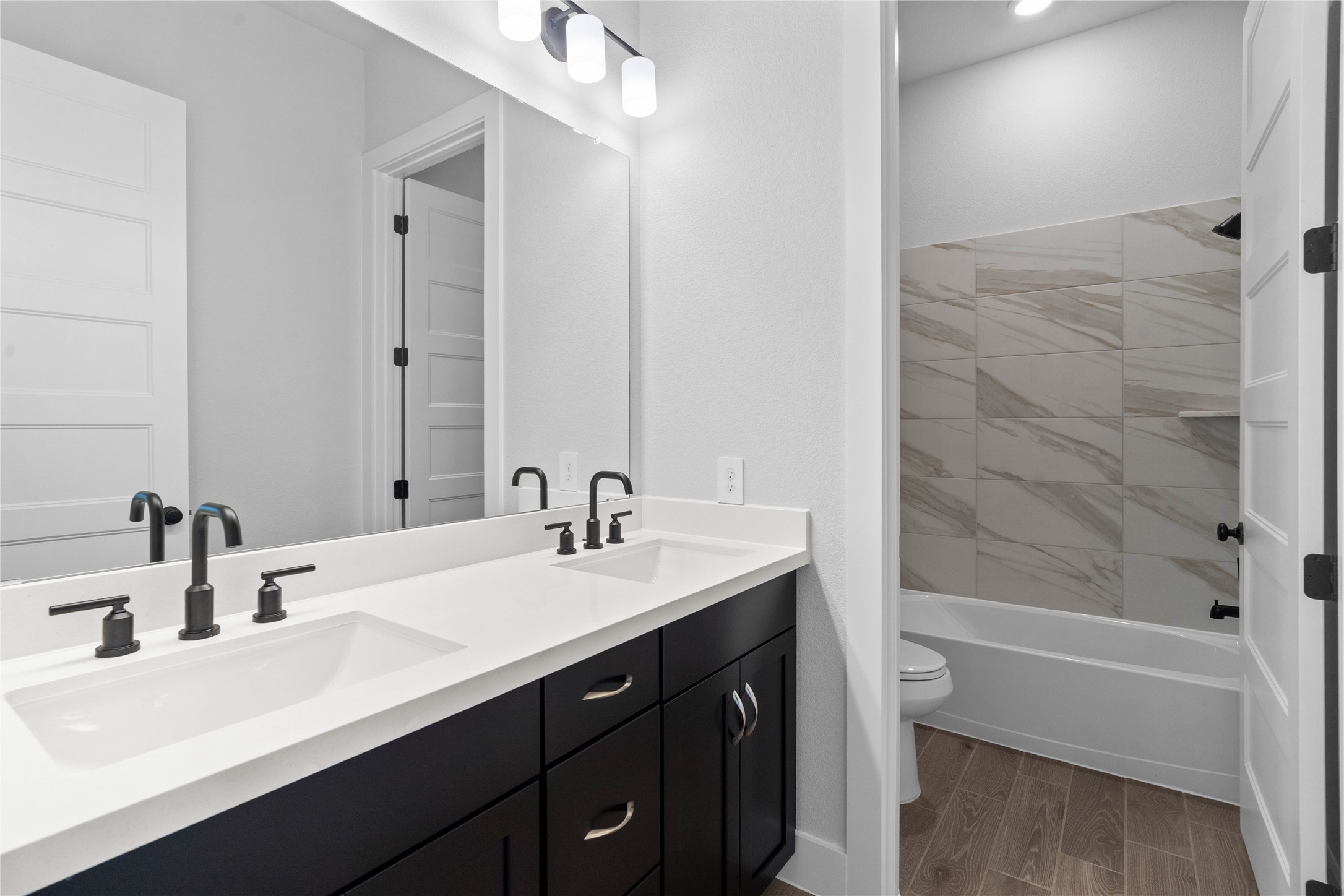 2114 Rowl Street Montgomery, TX 77316 - Photo 11 of 50 This well-appointed secondary bathroom features a sleek dual sink vanity, crisp white countertop, matte black modern fixtures, and tub/shower combination.