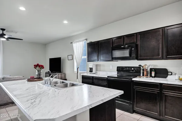 a kitchen with stainless steel appliances a sink dishwasher a stove top oven a refrigerator with island and chairs