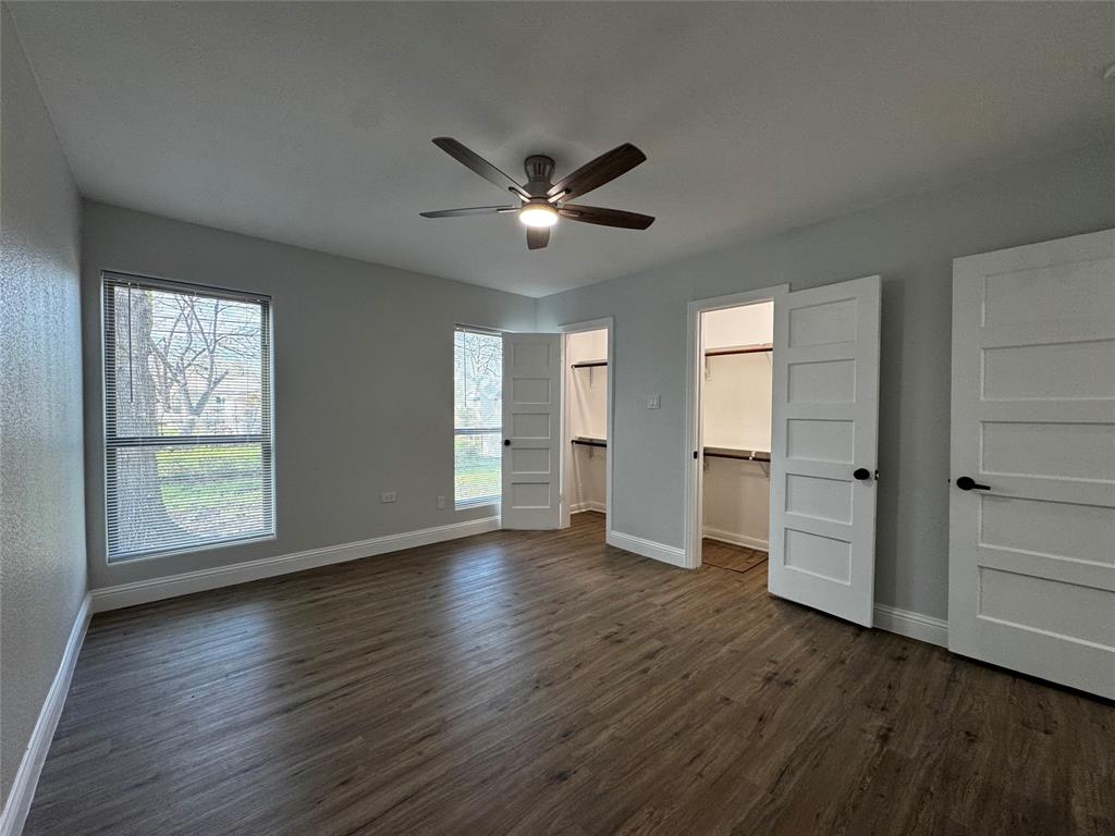 2909 Alexander Avenue Waco, TX 76708 - Photo 13 of 27 Unfurnished bedroom featuring a walk in closet, multiple windows, dark wood-type flooring, and ceiling fan