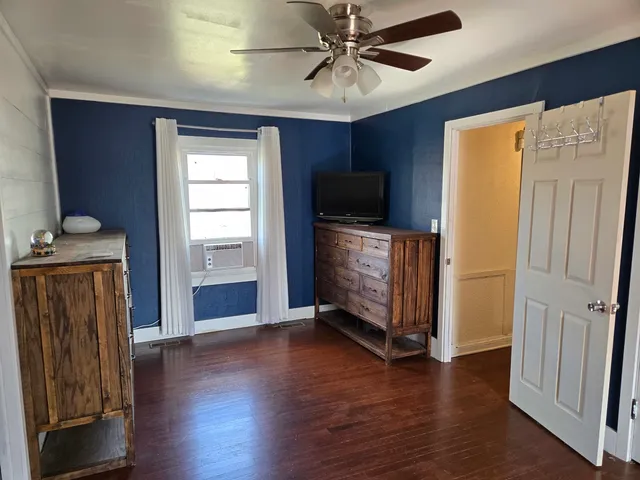 an empty room with wooden floor cabinet and windows