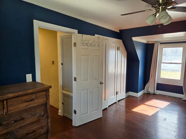 a view of front door with hallway and wooden floor