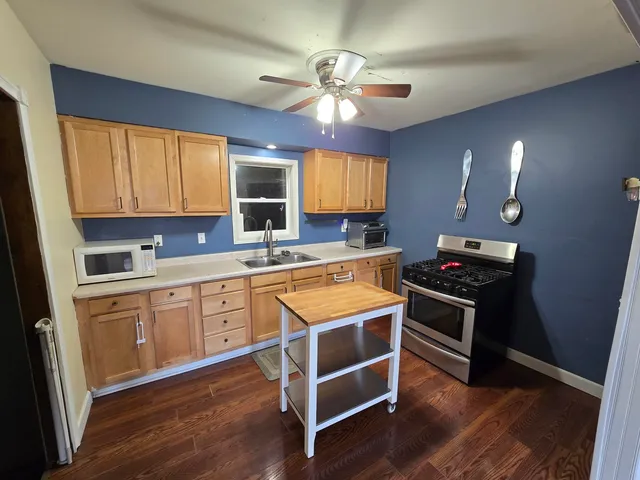 a kitchen with stainless steel appliances granite countertop a sink cabinets and wooden floor