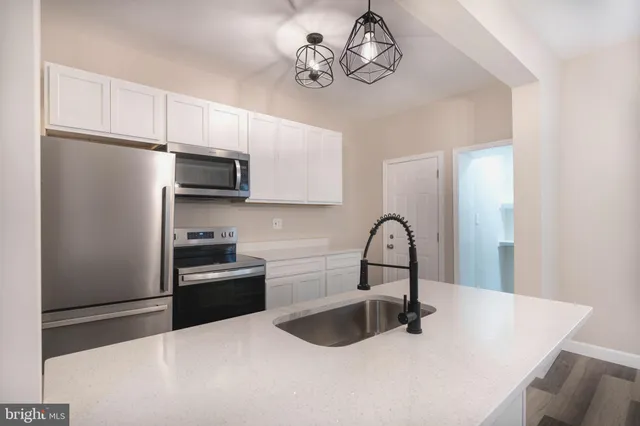 a kitchen with stainless steel appliances a sink a refrigerator and cabinets