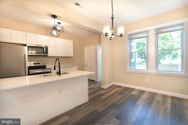 a large kitchen with stainless steel appliances a large counter top a stove a refrigerator and a window