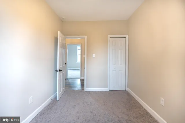 a view of an empty room with closet and a window