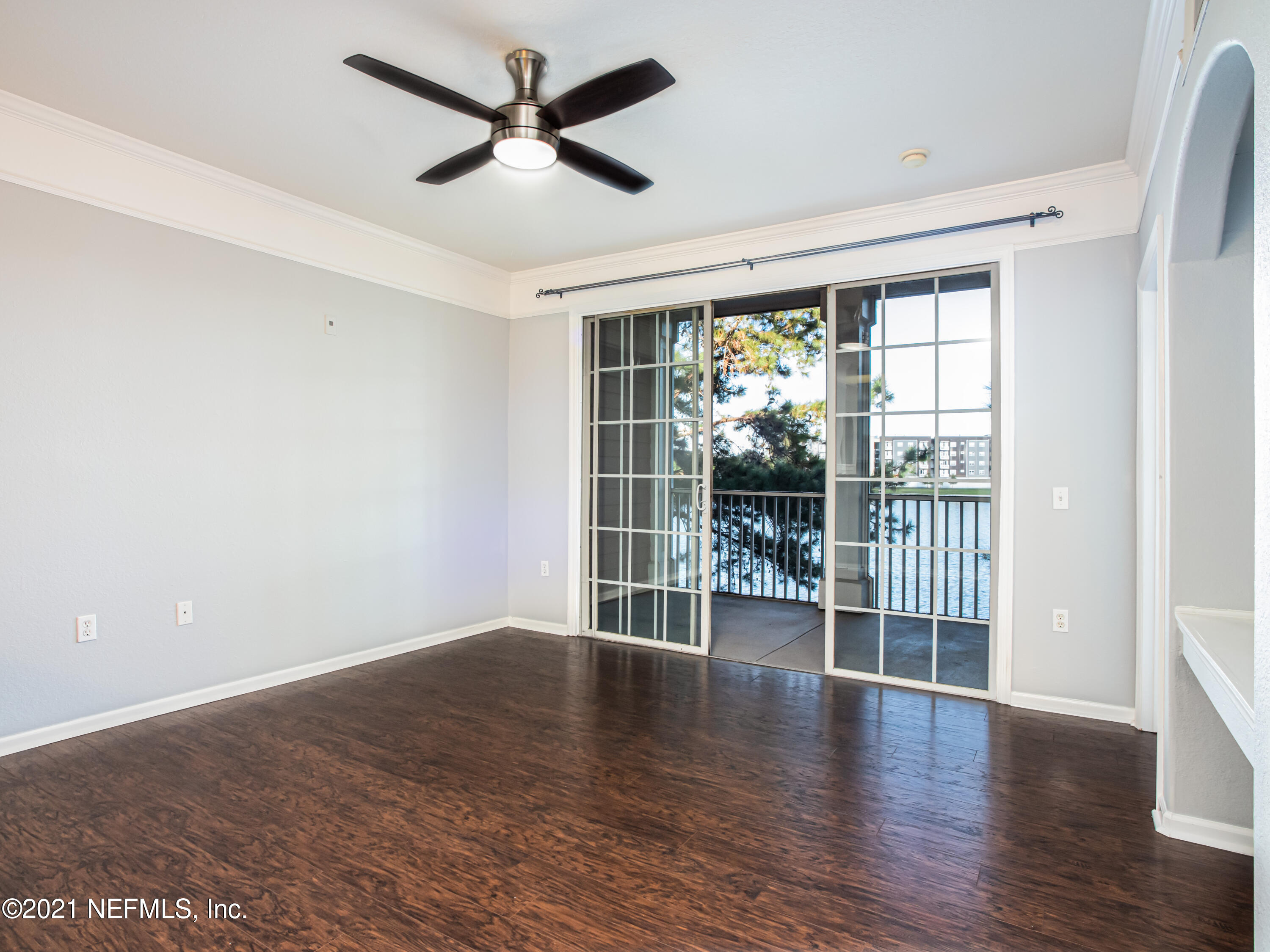 a view of empty room with wooden floor and fan