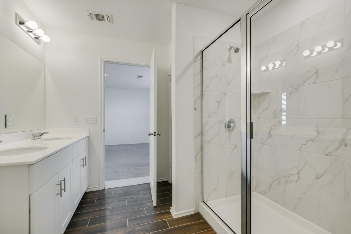 661 Pickrell Loop Georgetown, TX 78628 - Photo 15 of 27 a bathroom with a double vanity sink a mirror and a shower