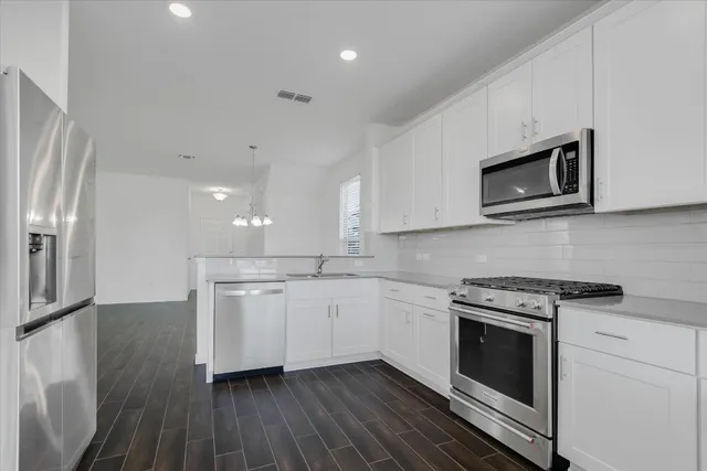 a kitchen with stainless steel appliances granite countertop a stove a microwave and a hard wood floors