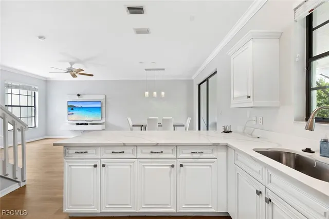 a white kitchen with sink and cabinets