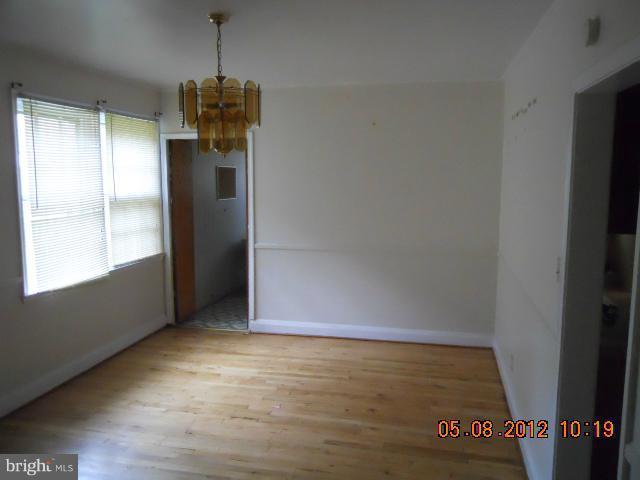 3922 Clarinth Road Baltimore, MD 21215 - Photo 5 of 10 an empty room with wooden floor and windows