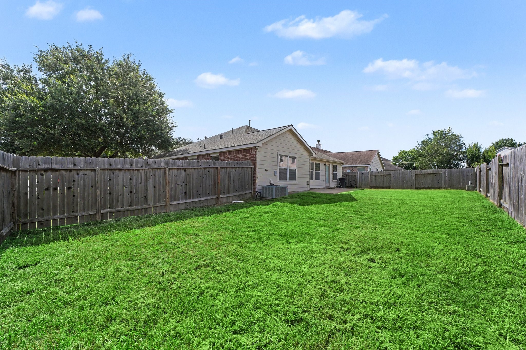 21427 Blooming Rock Lane Spring, TX 77379 - Photo 32 of 32 Spacious backyard with well-maintained lawn, wooden fencing, and ample room for outdoor activities. Ideal for families and pets.