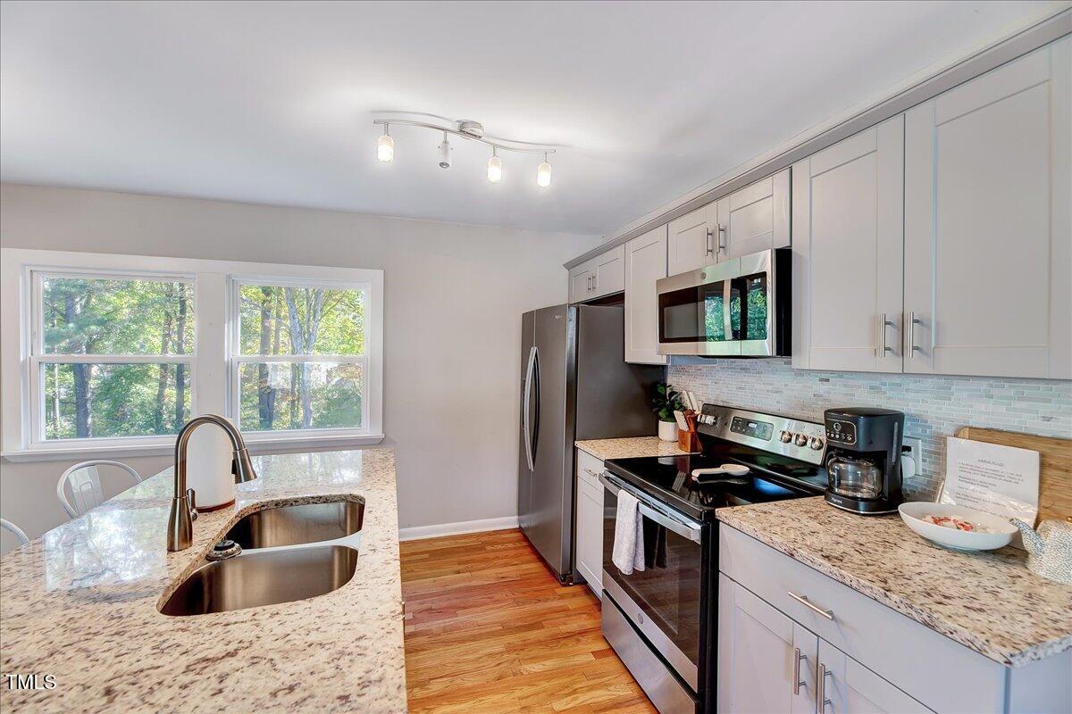 2809 Newark Drive Raleigh, NC 27610 - Photo 10 of 36 a kitchen with granite countertop kitchen island stainless steel appliances a sink stove and refrigerator