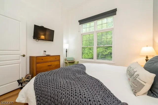 a bedroom with a bed and flat tv screen on the dresser