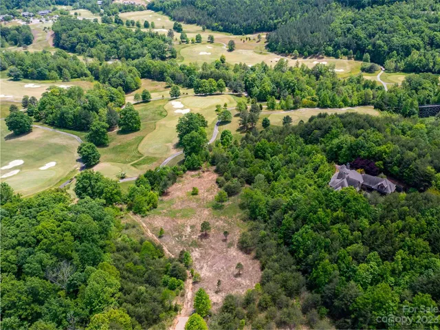 an aerial view of residential houses with outdoor space and trees all around