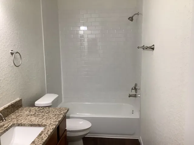 a bathroom with a granite countertop bathtub toilet and sink