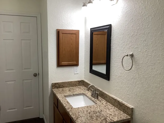 a bathroom with a granite countertop sink and a mirror