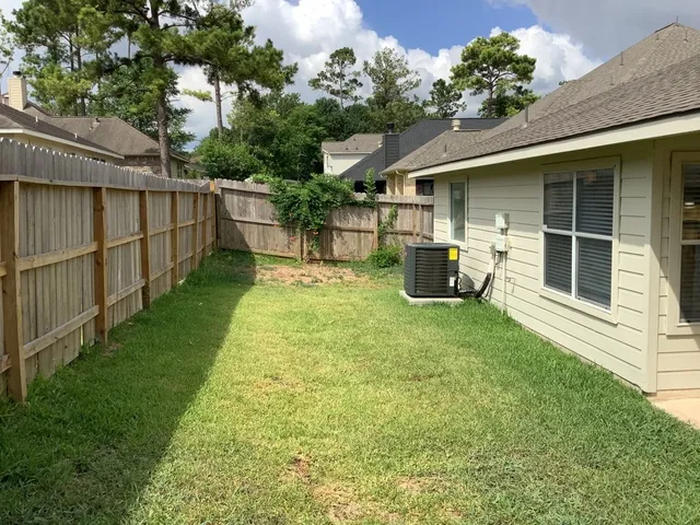 a view of a backyard with table and chairs potted plants and large tree