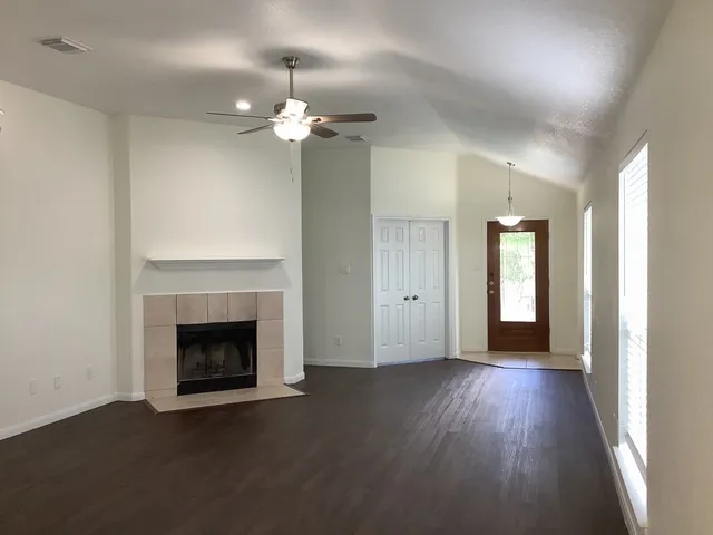 a view of an empty room with wooden floor and a fireplace