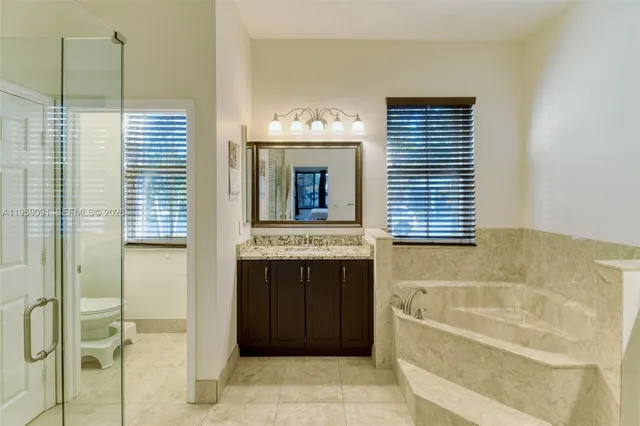 a bathroom with a granite countertop sink toilet and mirror
