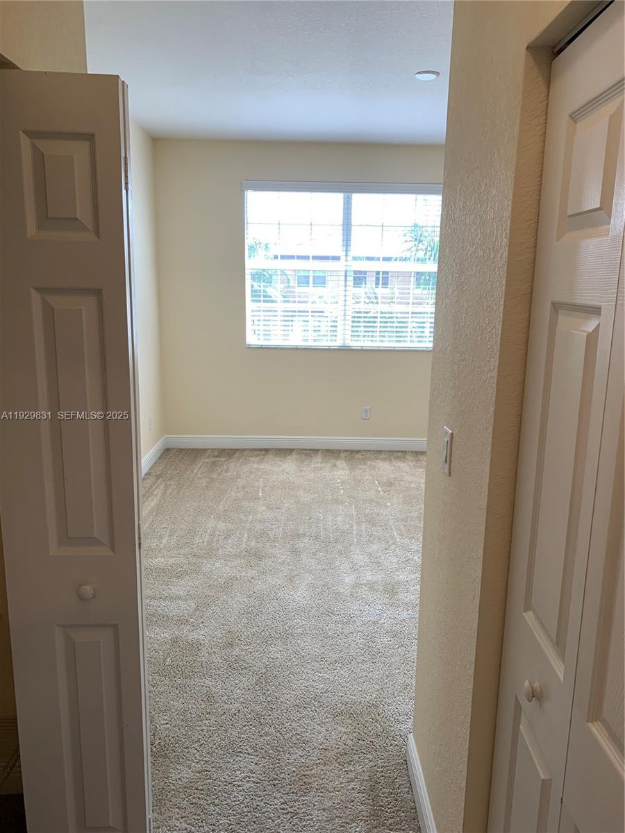 1044 Southwest 147th Avenue, Unit 10105 Pembroke Pines, FL 33027 - Photo 14 of 23 a view of an empty room with wooden floor and windows