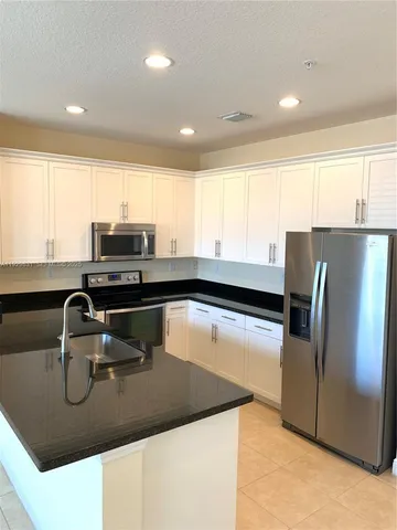 a kitchen with kitchen island a sink appliances and cabinets
