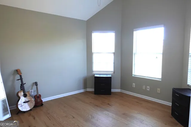 an empty room with wooden floor and windows
