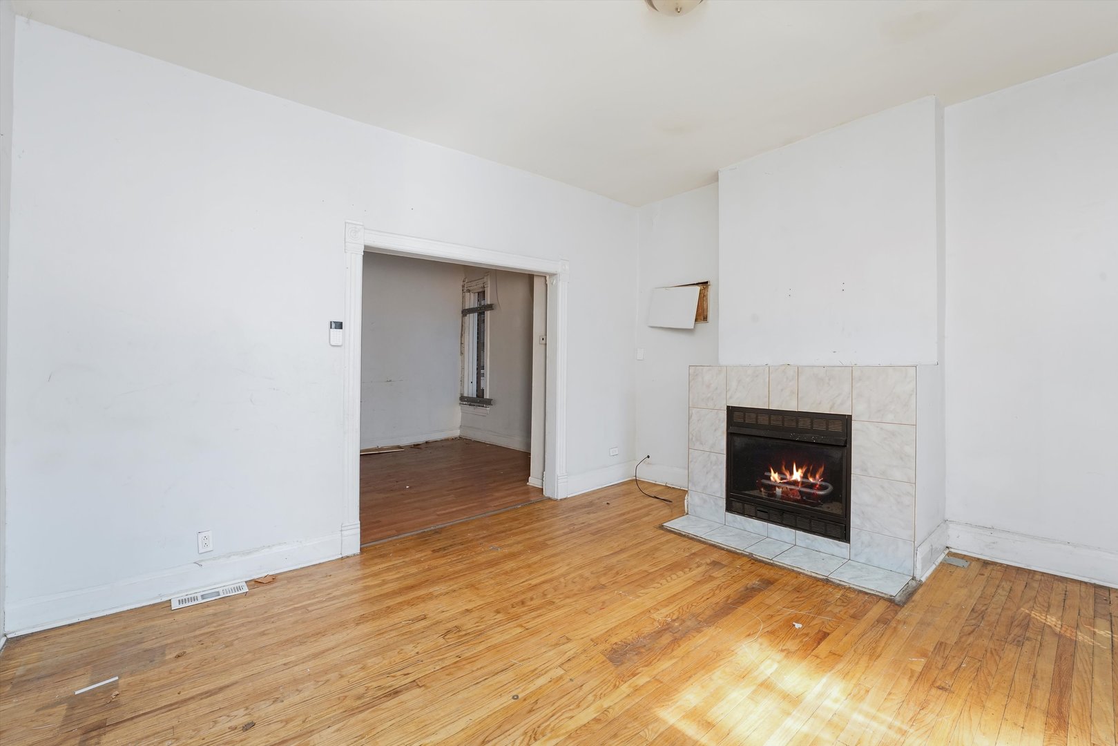 58 West 72nd Street Chicago, IL 60621 - Photo 4 of 28 a view of an empty room with wooden floor a fireplace and a window