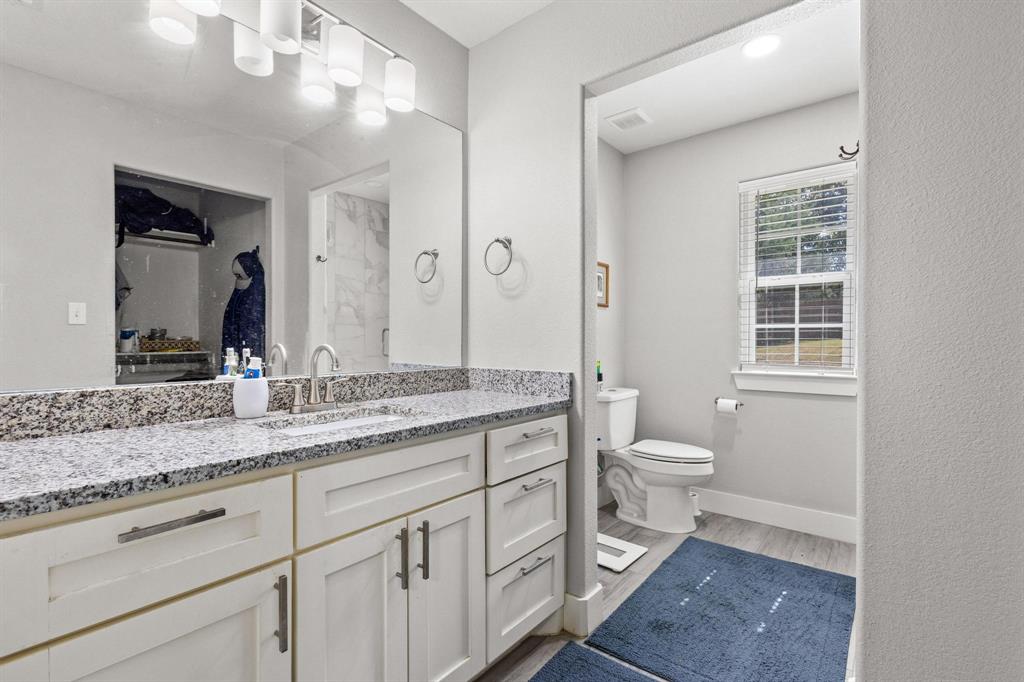 608 East Shepherd Street Denison, TX 75021 - Photo 20 of 31 Double vanity featuring a light granite countertop and white shaker-style cabinetry with brushed nickel hardware