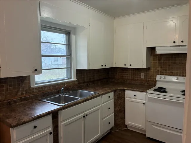 a kitchen with granite countertop white cabinets and white appliances