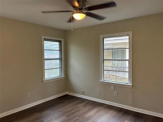a view of an empty room with window and wooden floor
