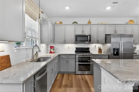 a kitchen with kitchen island granite countertop a sink counter top space appliances and cabinets