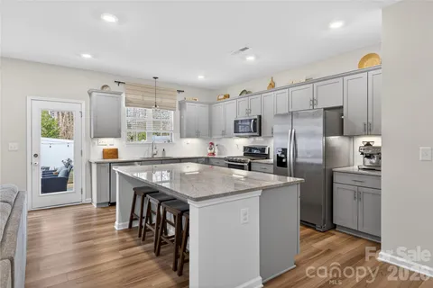 a kitchen with stainless steel appliances granite countertop a table chairs refrigerator and microwave