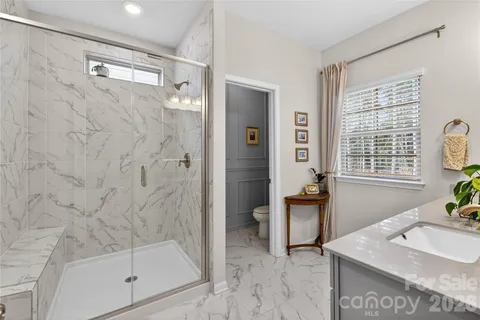 a bathroom with a granite countertop sink a mirror a bathtub and next to a window