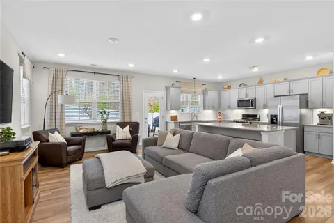 a living room with furniture kitchen view and a large window