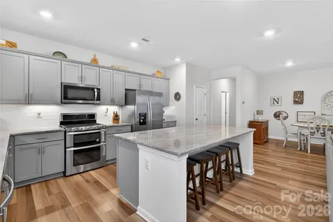 a kitchen with stainless steel appliances granite countertop a stove a sink a microwave a dining table and chairs