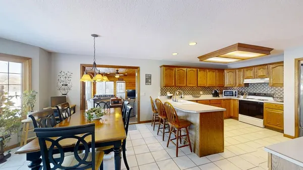 a kitchen with stainless steel appliances kitchen island granite countertop a table chairs and a view of living room