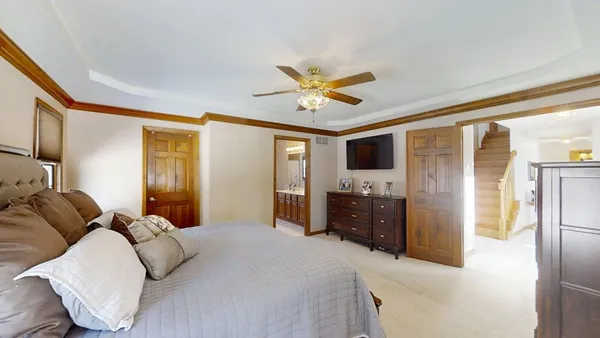 a bedroom with a bed and a chandelier with a flat tv screen