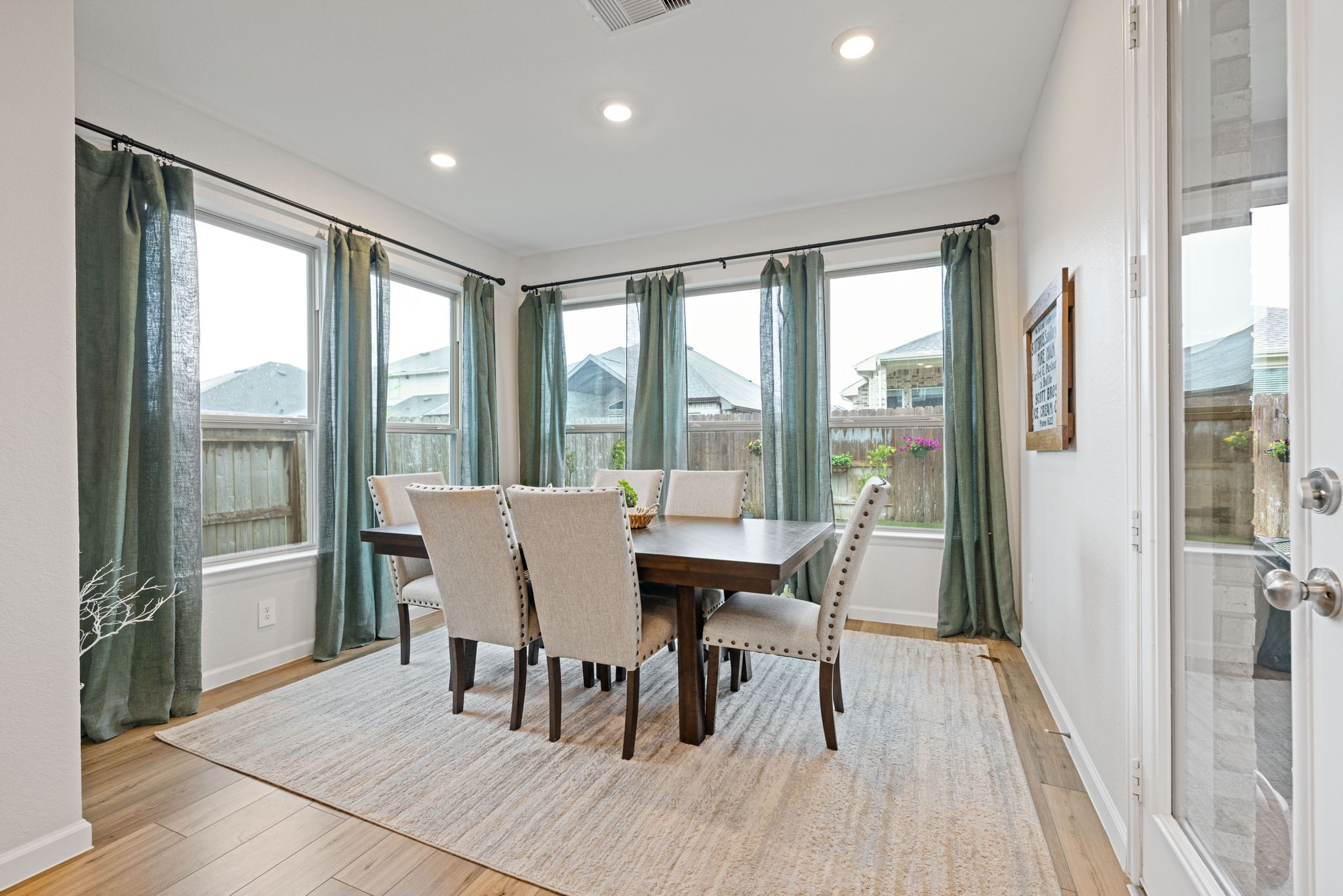 18323 Tiger Flowers Drive Conroe, TX 77302 - Photo 16 of 49 Bright and inviting dining area with large windows, elegant light curtains, and a stylish wooden table set on a neutral rug, offering a cozy space for gatherings.
