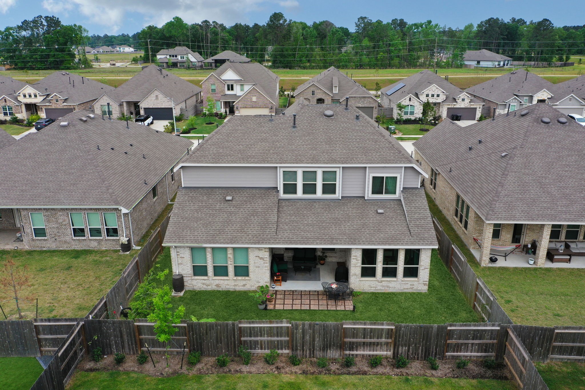 18323 Tiger Flowers Drive Conroe, TX 77302 - Photo 45 of 49 This aerial photo showcases a two-story suburban home with a fenced backyard, patio, and well-maintained lawn. The house is surrounded by similar properties, offering a sense of community in a neatly arranged neighborhood.